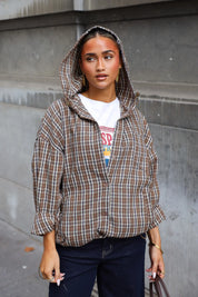 Camel geruite blouse met lange mouwen capuchon en zakken aan de voorkant gecombineerd met een donkere jeans