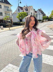 Model draagt blouse bloemen print roze buiten op straat