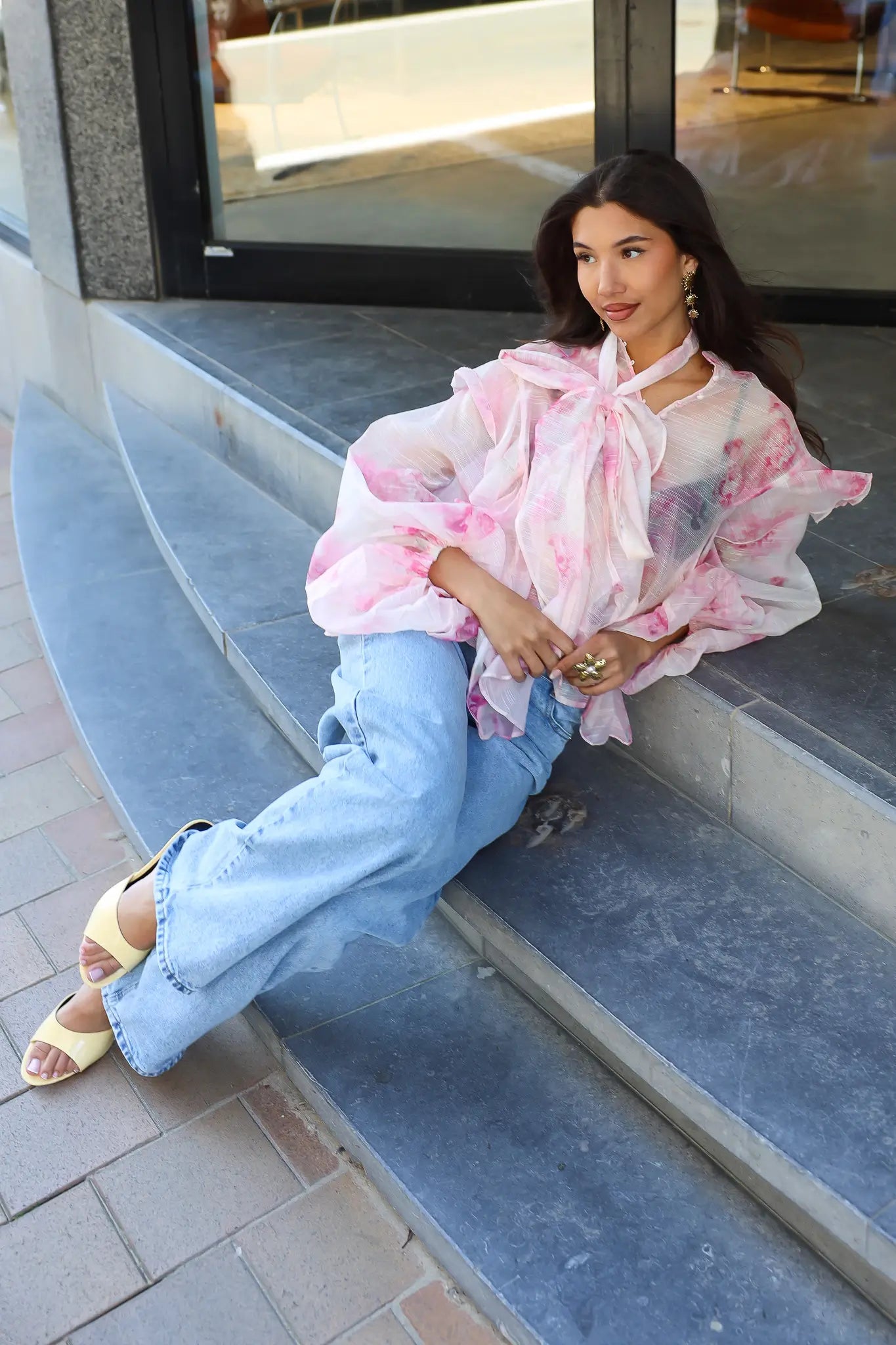 Model zit op trap met blouse bloemen print roze