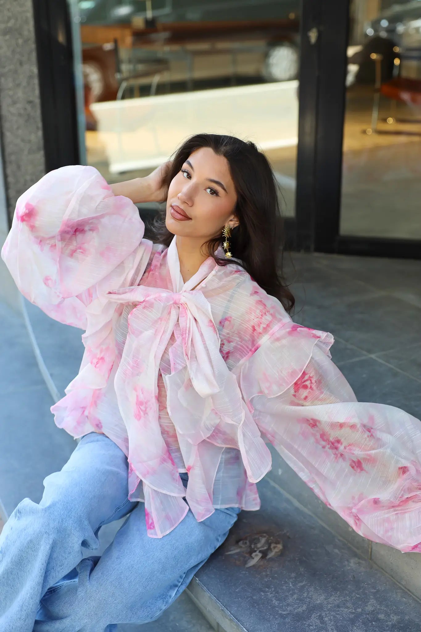 Model draagt blouse bloemen print roze zittend