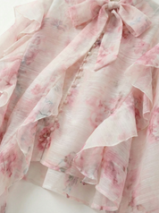 Detail van ruches en bloemenprint van de blouse