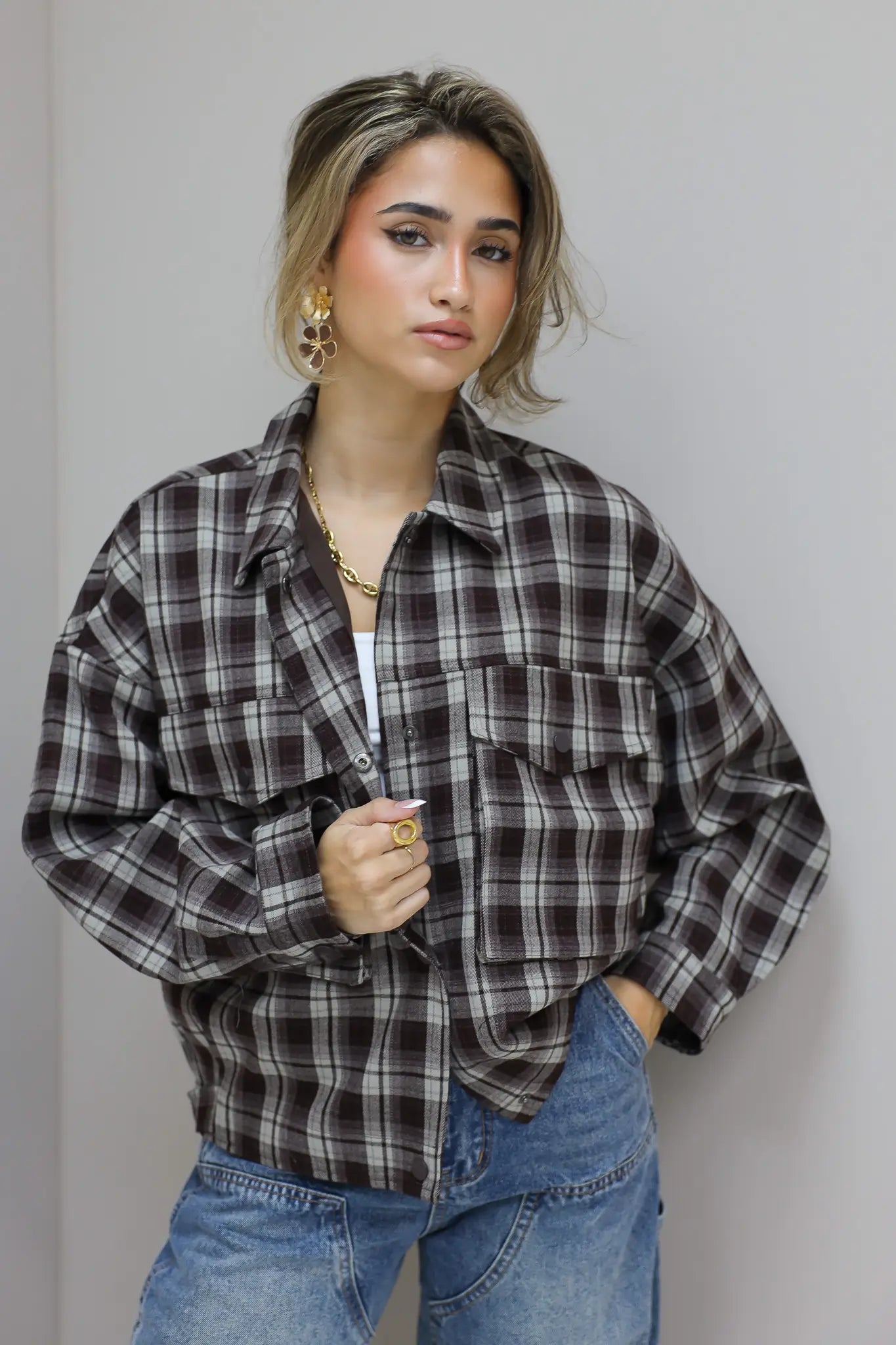 close up van vrouw met bruine geruite blouse en jeans, hand aan blouse