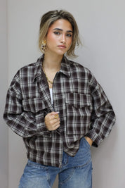 close up van vrouw met bruine geruite blouse en jeans, hand aan blouse