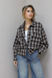 vrouw met bruine geruite blouse houdt kraag vast en kijkt opzij