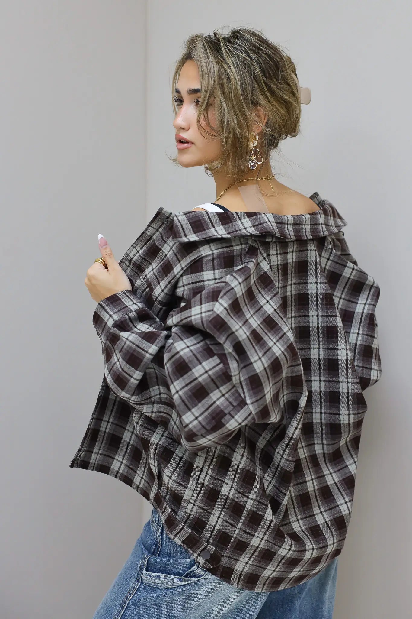 zijaanzicht van vrouw met bruine geruite blouse en losse jeans