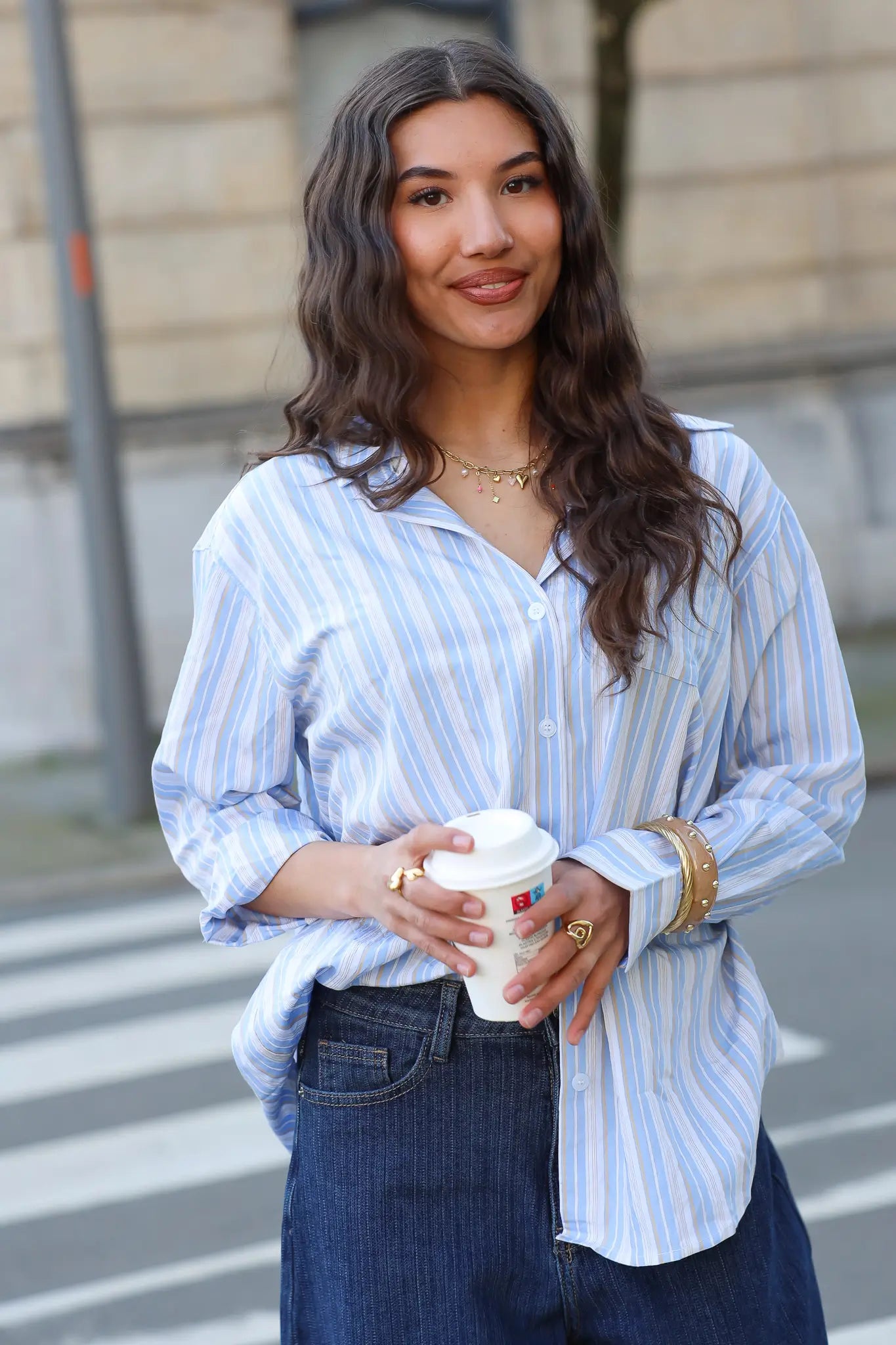 model met blauw wit gestreepte blouse en jeans met koffiebeker