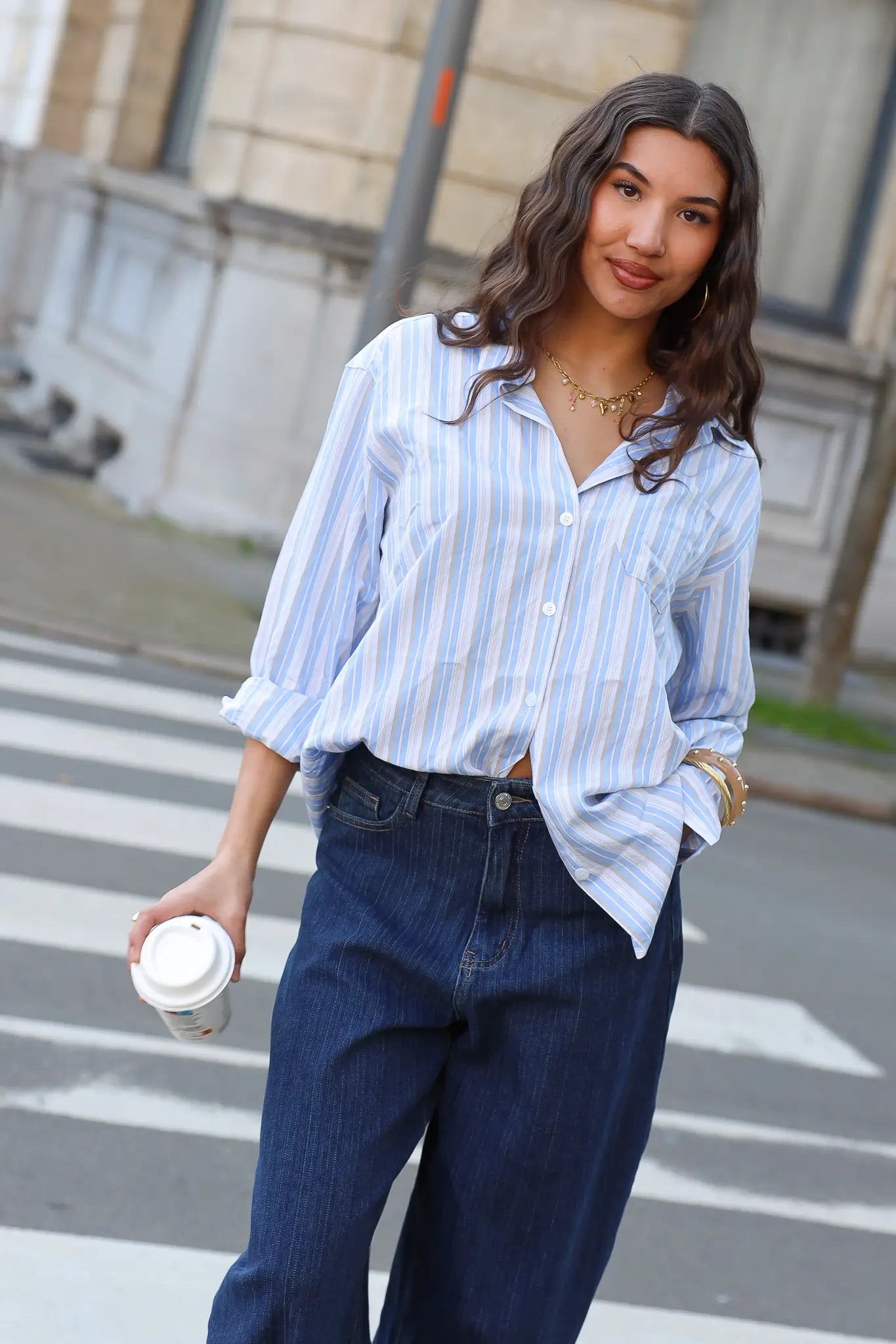 model draagt blauw wit gestreepte blouse met donkere jeans op straat