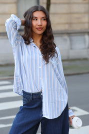 model draagt blauw wit gestreepte blouse met jeans op straat