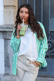 model draagt groen wit gestreepte blouse met witte top en broek