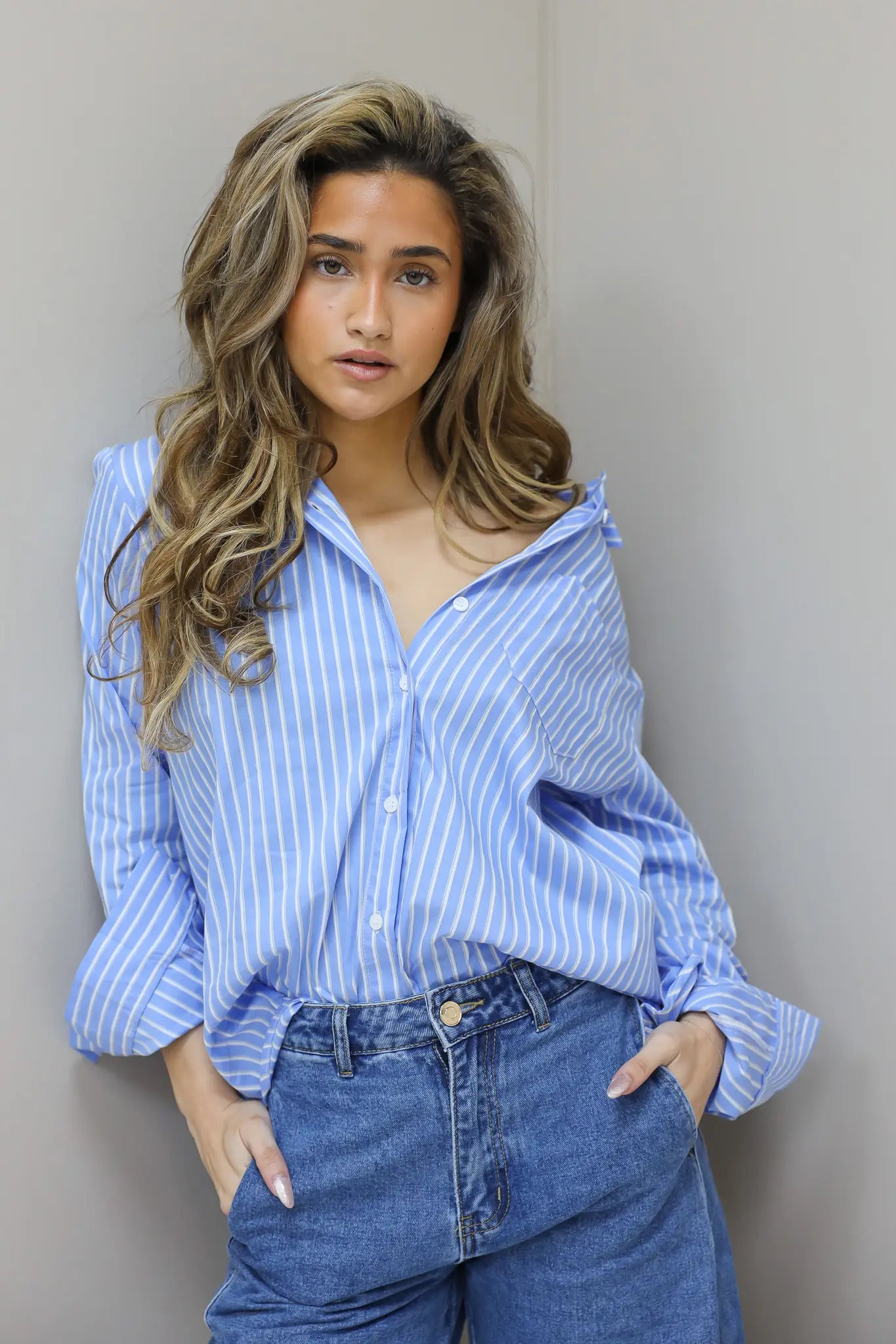 model draagt lichtblauwe blouse met verticale strepen