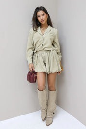 Beige blouse met rok en laarzen buiten voor een gebouw