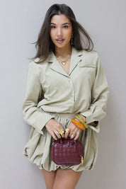 Beige blouse met kraag van voren gefotografeerd bij grijze muur