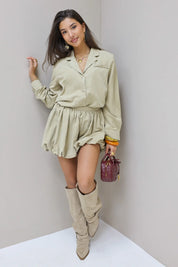 Model buiten bij deur in beige blouse en rok met tas