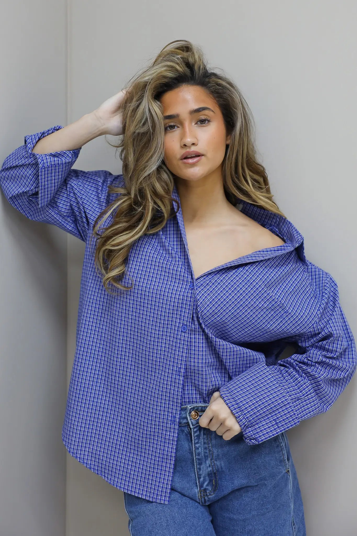 model draagt blauwe blouse met kleine ruit print en schoudervulling