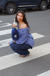 model draagt blauwe ruit blouse dames zittend outfit ladylike