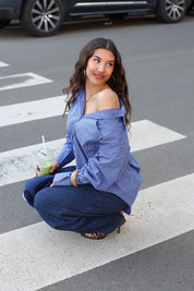 model draagt blauwe ruit blouse dames zittend op straat ladylike