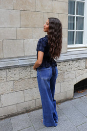 Achteraanzicht van een donkerblauwe geruite blouse met korte mouwen, gedragen bij een blauwe wide leg jeans.