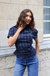 Vooraanzicht van een blauw geruite blouse met korte mouwen en getailleerde pasvorm, gecombineerd met een lichtblauwe jeans.