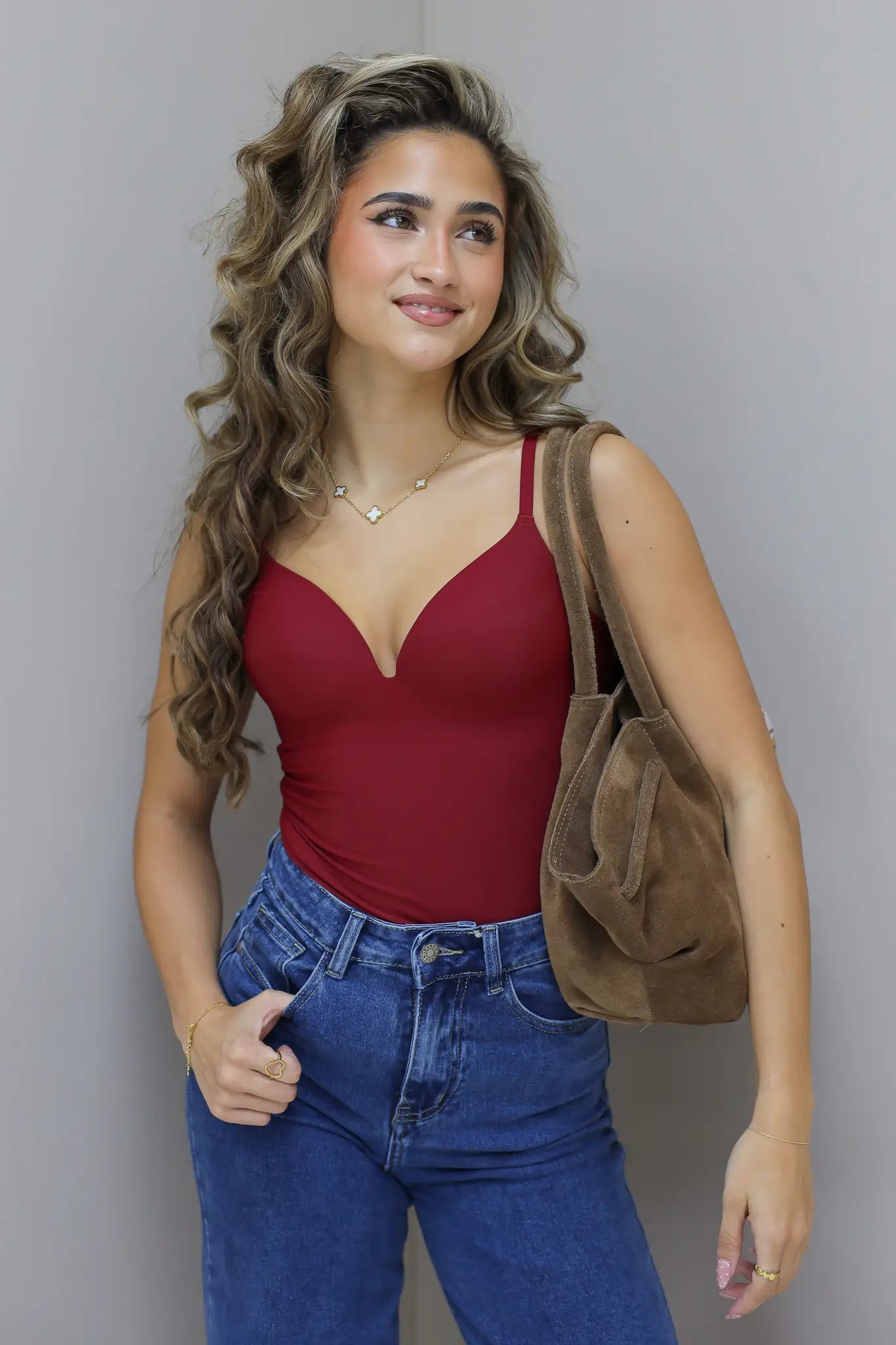 Model kijkt opzij met hand in zak, tas zichtbaar aan schouder