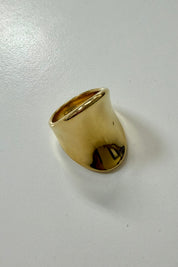 Brede goudkleurige ring op lichte achtergrond