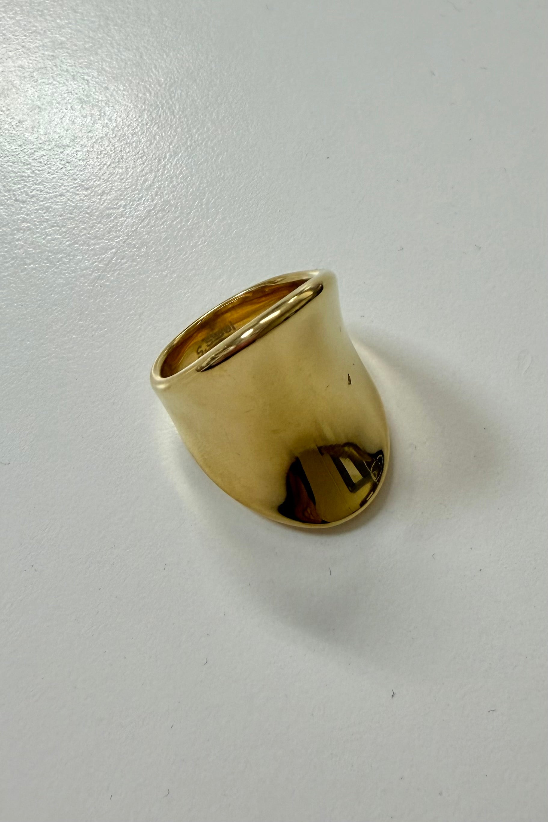 Brede goudkleurige ring op lichte achtergrond