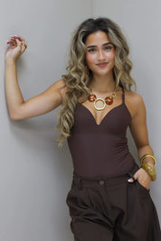 Bruine bodysuit met hand in zij poserend in de studio