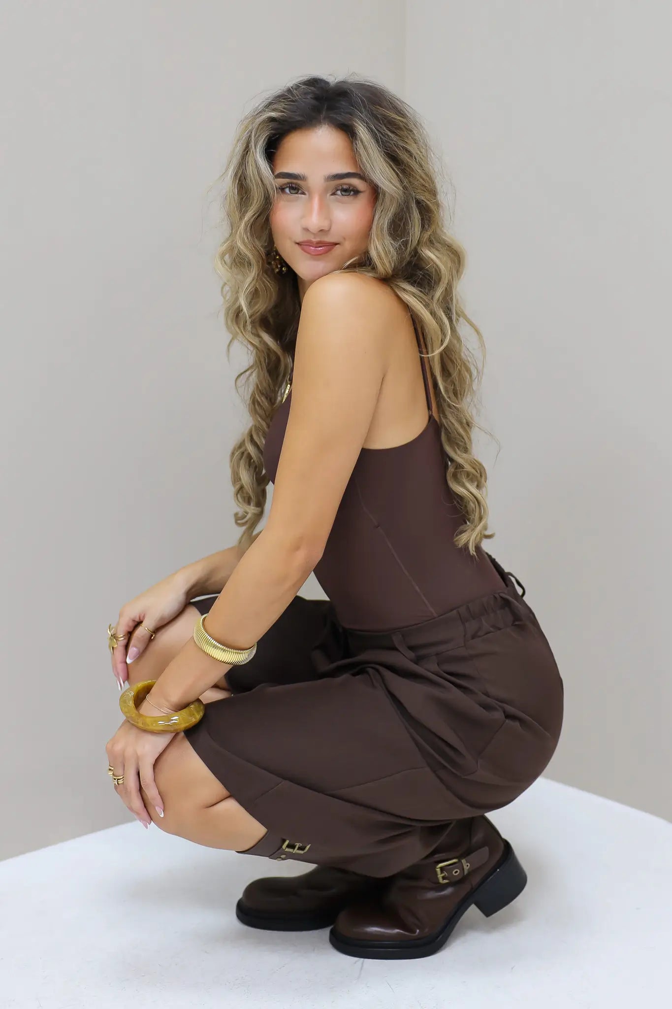 Bruine bodysuit met hand omhoog poserend in de studio