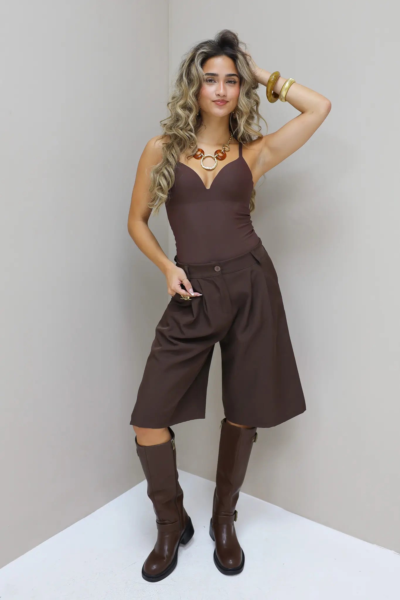 Bruine bodysuit met culotte en laarzen in de studio