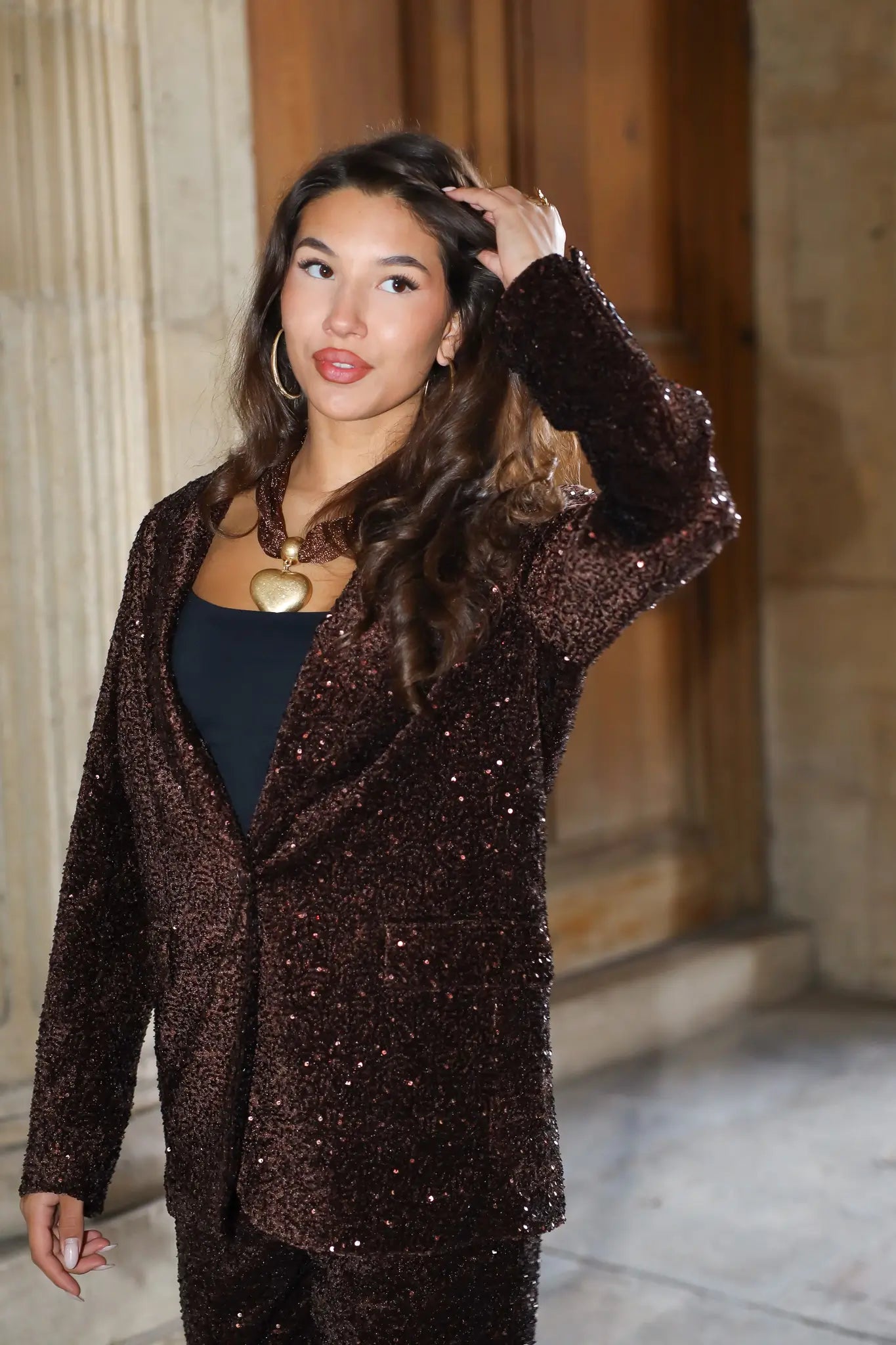 bruin party pak model poseert met hand omhoog voor stenen wand