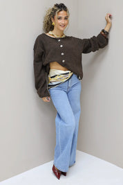 model leunt tegen muur in bruin vest en jeans