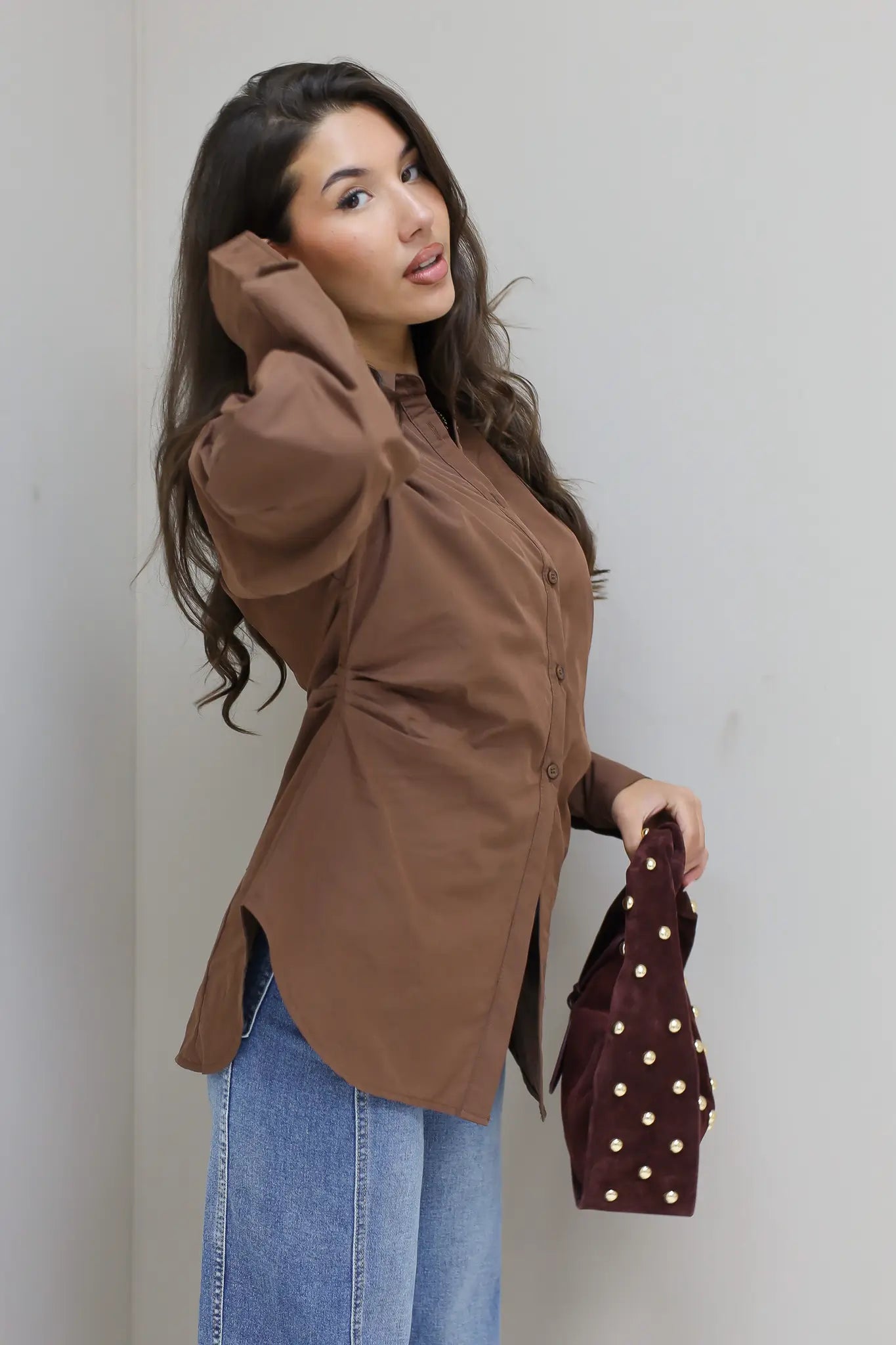 bruine blouse model staand met hand in zij