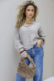 model met grijze trui en jeans draagt de bruine faux fur tas naast zich