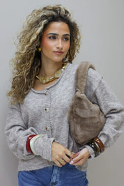 model met grijze trui houdt de bruine faux fur tas dicht tegen zich aan