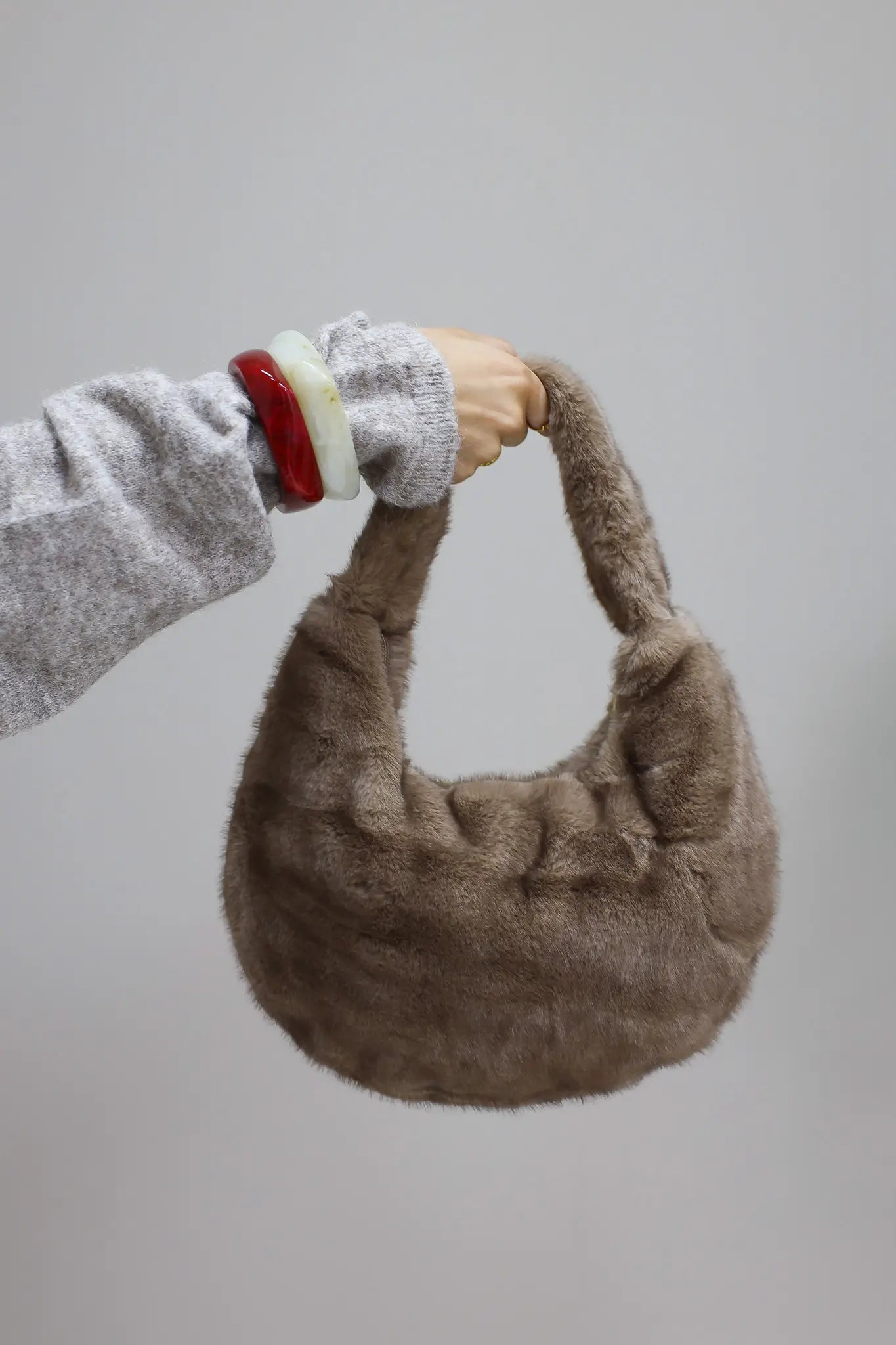 bruine faux fur tas omhoog gehouden tegen lichte achtergrond