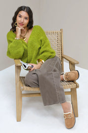 Model zit op stoel met bruine instappers met bontvoering en gouden gesp