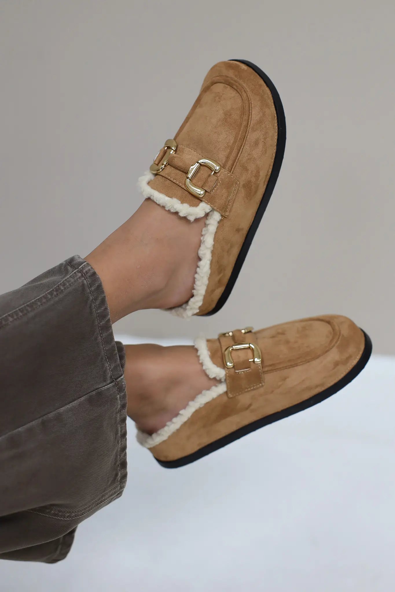 Bruine instapper met bontvoering en goudkleurige gesp op witte achtergrond