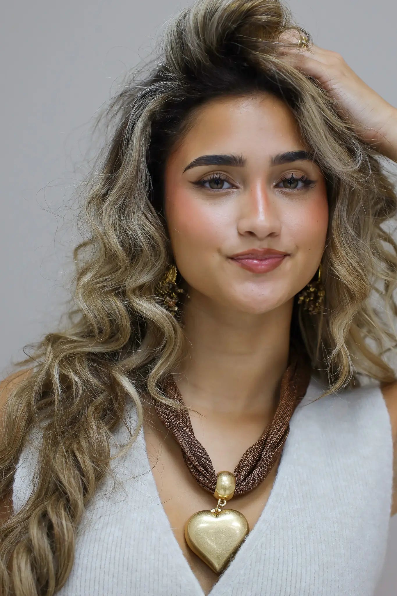 foto van bruine ketting met groot goudkleurig hart aan hals van model