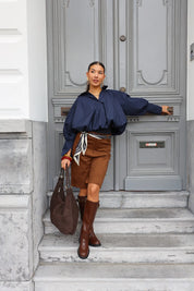 Close-up van bruine laars met gespen en lichte trenchcoat