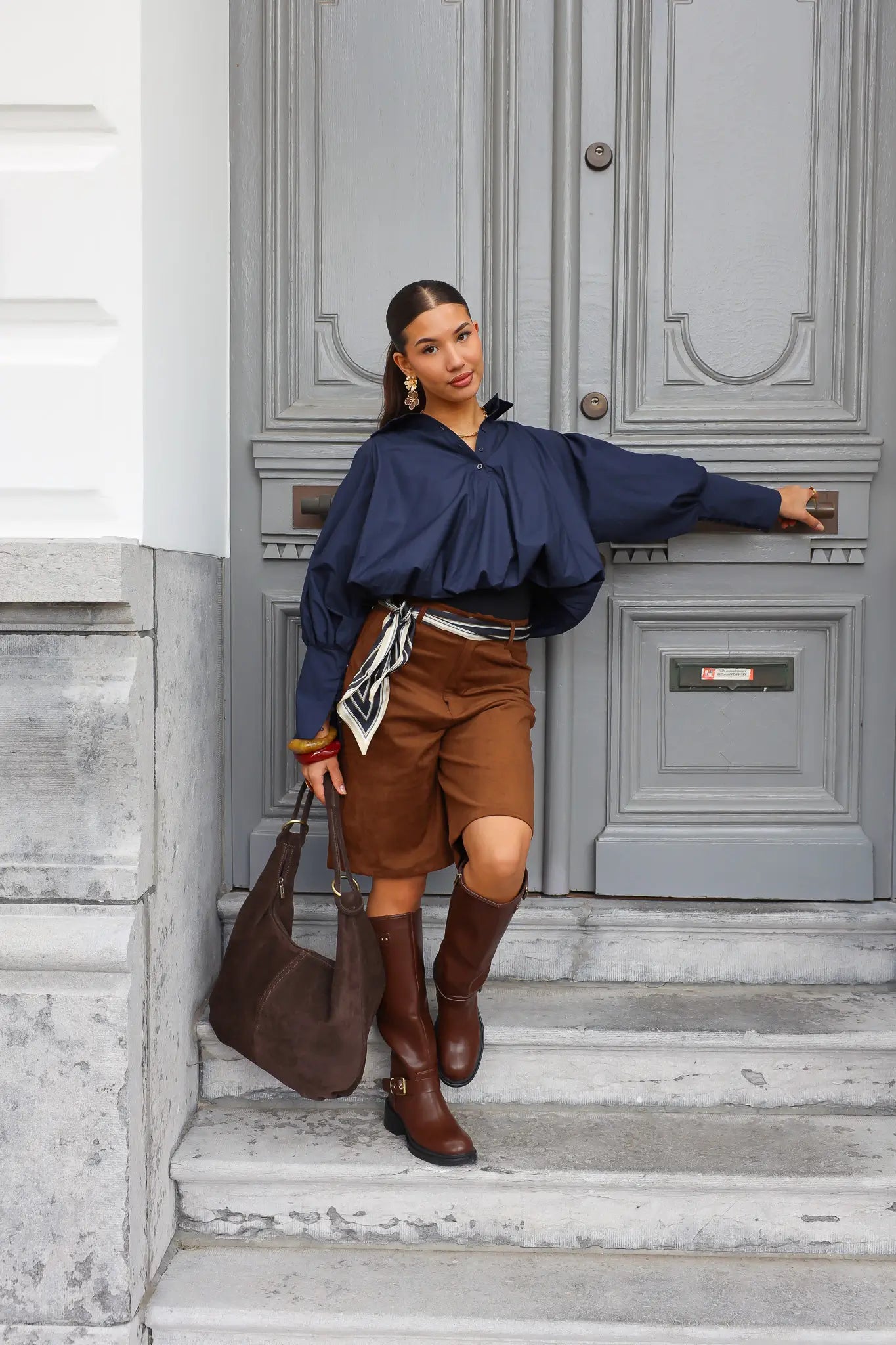 Model draagt bruine laarzen met rok en tweed jasje