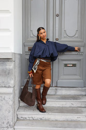 Model draagt bruine laarzen met rok en tweed jasje