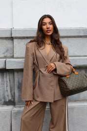 Model draagt bruine oversized blazer met bijpassende pantalon op straat