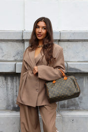Model met bruine oversized blazer, pantalon en designer handtas