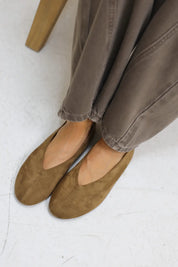 Close up van benen met bruine suède ballerina’s