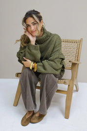 Model met groene trui op een stoel met bruine suède ballerina’s