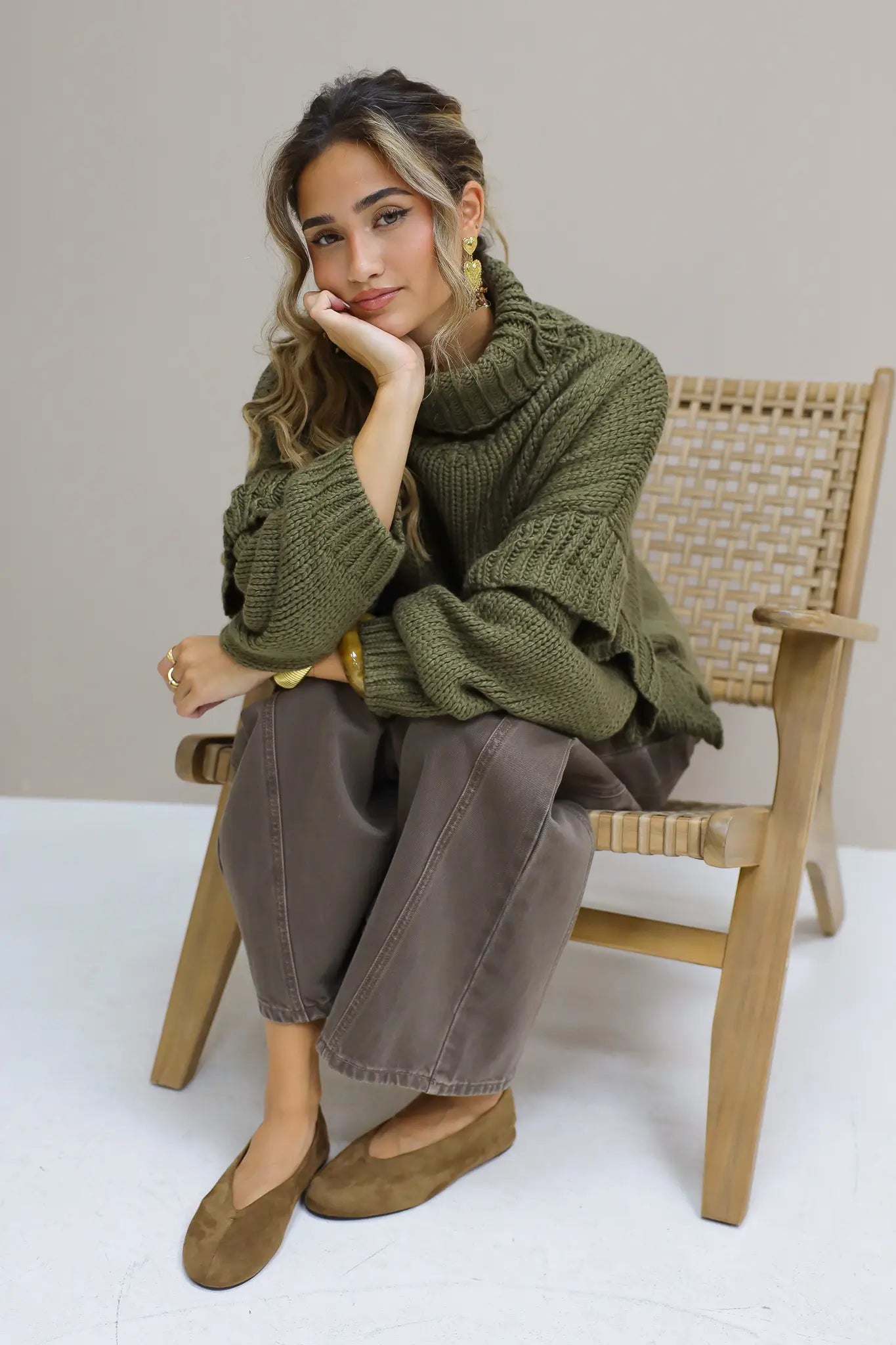 Model zit op een stoel met bruine suède ballerina’s