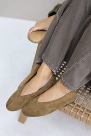 Gekruiste voeten met bruine suède ballerina’s