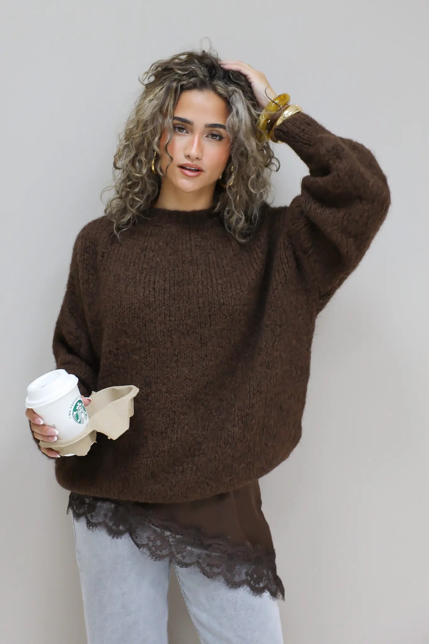 model met trui in nonchalante pose, hand in haar en mok in hand