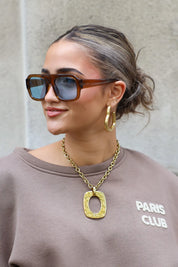 model met bruine zonnebril kijkt naar voren en glimlacht licht