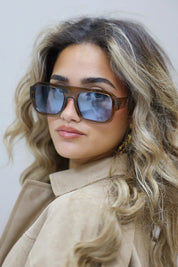 model raakt haar zonnebril aan met lichte glimlach