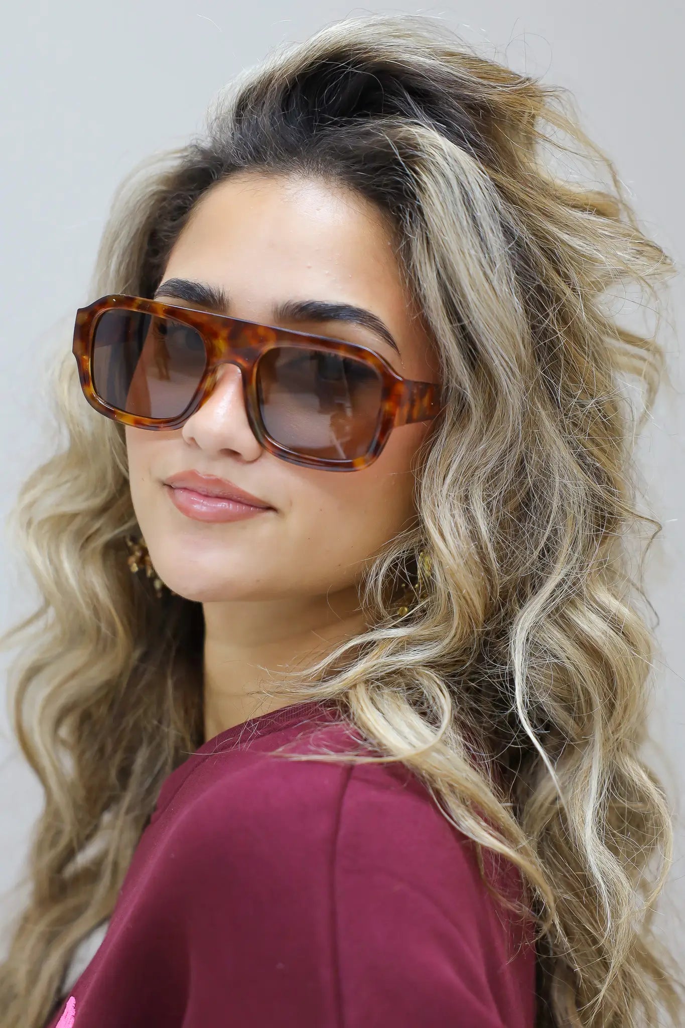 model met los haar en bruine zonnebril kijkt ontspannen naar voren